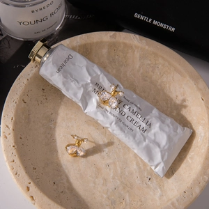 Close-up of golden bee earrings with sparkling zircon wings on a marble tray