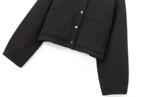 Detail of black wool-like bomber jacket featuring silver snaps and large patch pockets