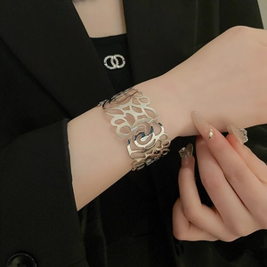Close-up of wide silver cuff bracelet with intricate hollow rose pattern on female model