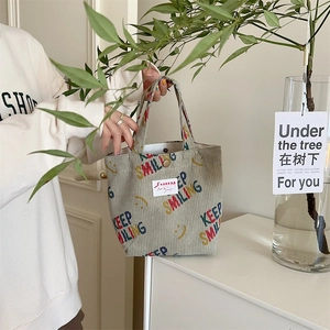 Macro detail of corduroy tote bag featuring Keep Smiling print and brand label