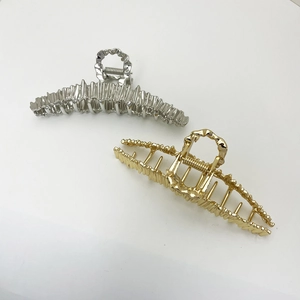 Detail shot of oversized irregular metal hair claws with golden and silver crinkle finish