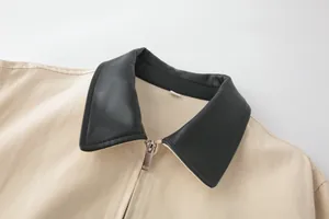 Detailed close-up of beige jacket featuring contrast black leather lapels and silver zipper