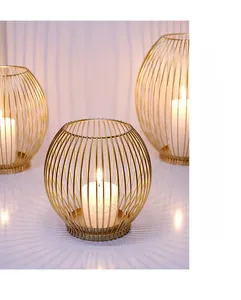 Close-up of golden geometric metal candle holder with lit white pillar candle decoration