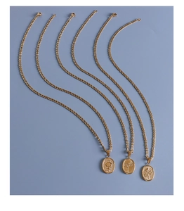 Gros plan de pendentifs ovales dorés avec motifs floraux de rose et tulipe en relief