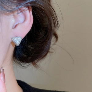 Gros plan de boucles d'oreilles triangulaires argentées serties de zircons sur un modèle