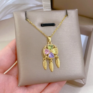 Detail of dreamcatcher pendant with multicolor crystals and golden feathers on a chain