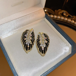 Macro shot of vintage leaf earrings featuring black enamel and sparkling rhinestones
