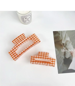Detail view of orange plaid acrylic hair claws in medium and large sizes