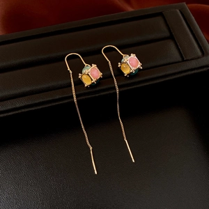 Detail of gold drop earrings with pink, yellow and blue crystal cube charms