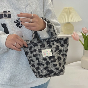 Detail of leopard print plush handbag with embroidered patch and soft handle