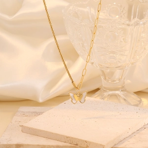 Elegant gold butterfly necklace with white shell pendant on a premium stone pedestal