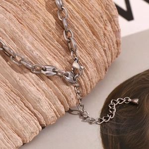 Macro view of silver coffee bean link bracelet with lobster clasp on natural stone surface
