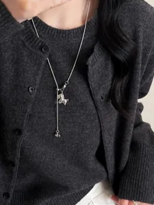 Close-up of silver horse pendant necklace worn on a grey sweater with elegant tassel details