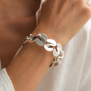 Detailed view of silver organic S-shaped twisted metal link bracelet on model wrist