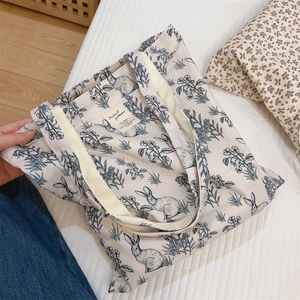 Detail of minimalist cream canvas tote bag featuring black and white rabbit floral print