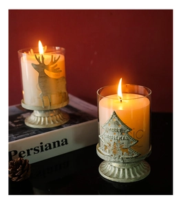 Close-up of reindeer and Christmas tree glass candle holders with metal base on red background