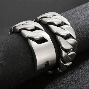 Macro shot of silver Cuban link bracelet with brushed metal finish on a black display
