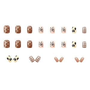 Short square press-on nails with cow print, bow knots, and heart patterns in warm tones