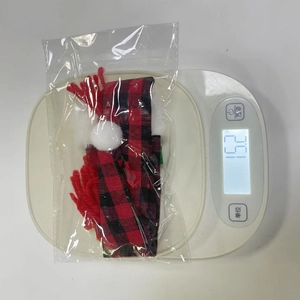 Quality check view of red and black plaid Christmas bottle cover weighing 15.2g on a scale