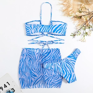 Flat lay of blue striped bikini set with mesh skirt, straw hat, and beach accessories