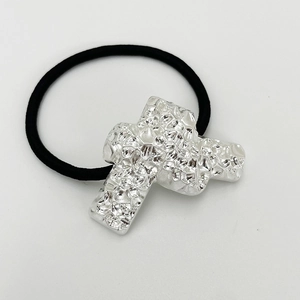 Detail shot of silver metal cross charm with hammered texture on black elastic hair tie