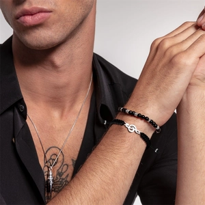 Close-up of black braided rope bracelet with music note charm and bead jewelry on wrist