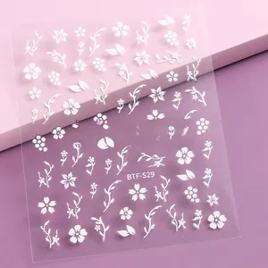 Detail of white embossed cherry blossom nail stickers with floral patterns on pink background
