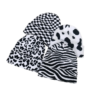 Detail of four knit beanies with checkerboard, cow, leopard, and zebra patterns