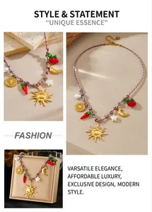 Close-up of gold sun and moon pendants on a woven necklace with cherry and chili accents