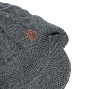 Détail du bonnet d'hiver gris foncé en maille torsadée avec visière et écusson