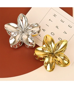 Macro shot of gold and silver metal flower claw clips with a high-polished mirror finish