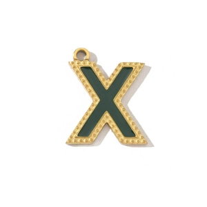 Detail of vintage gold-plated letter X pendant with dark green inlay and textured finish