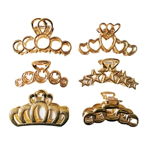 Set of six gold metal hair claws in heart, star, smile, and crown shapes on white background