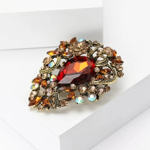 Detail of vintage gold alloy brooch with large teardrop amber stone and rhinestones