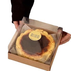 Basque cheesecake in a clear plastic and kraft paper box with a yellow round sticker