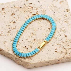 Detail of 18K gold plated bracelet with turquoise stones on travertine stone