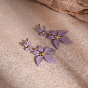 Vue détaillée des boucles d'oreilles fleurs violettes mates avec perles dorées sur pierre