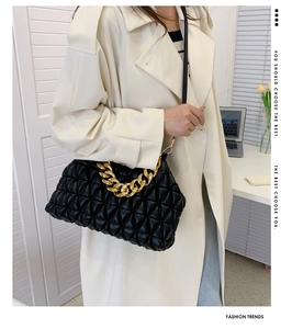 Close-up of black quilted shoulder bag with chunky gold chain and textured leather