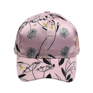 Close-up of pink satin baseball cap featuring delicate black floral lines and colorful prints