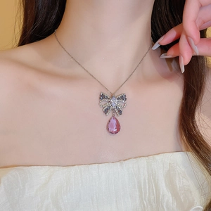 Close-up of butterfly pendant with pink teardrop crystal on a silver chain necklace