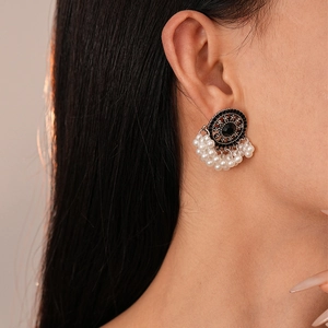 Detail shot of vintage ethnic style earrings with black stone and pearl tassels on a model