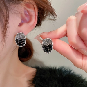 Détail de boucles d'oreilles ovales en cristal noir avec tige en argent et strass gris