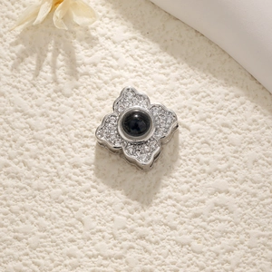 Macro shot of clover-shaped silver pendant with black gemstone and pavé zircons