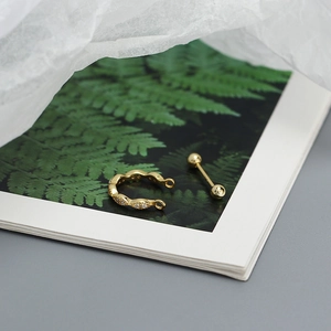 Macro detail of a gold S925 silver geometric threaded stud earring on a floral card