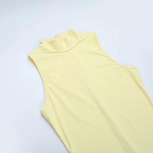 Dettaglio del top giallo a collo alto con chiusura a zip invisibile sul retro del capo