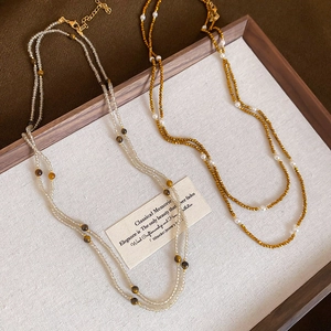 Detail of layered tiger eye beaded necklace with faceted stones on a fabric tray