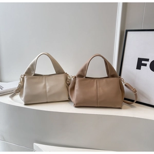 Detail of minimalist leather handbags in beige and brown with elegant side pleats
