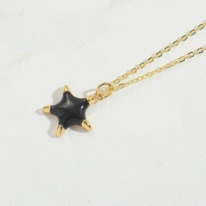 Detailed view of pentagram pendant with black enamel finish on a gold link chain