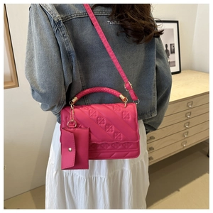 Pink quilted shoulder bag detail with woven handle and small detachable coin purse charm