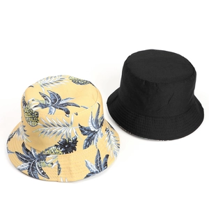Detail of yellow tropical pineapple print and solid black cotton reversible bucket hats